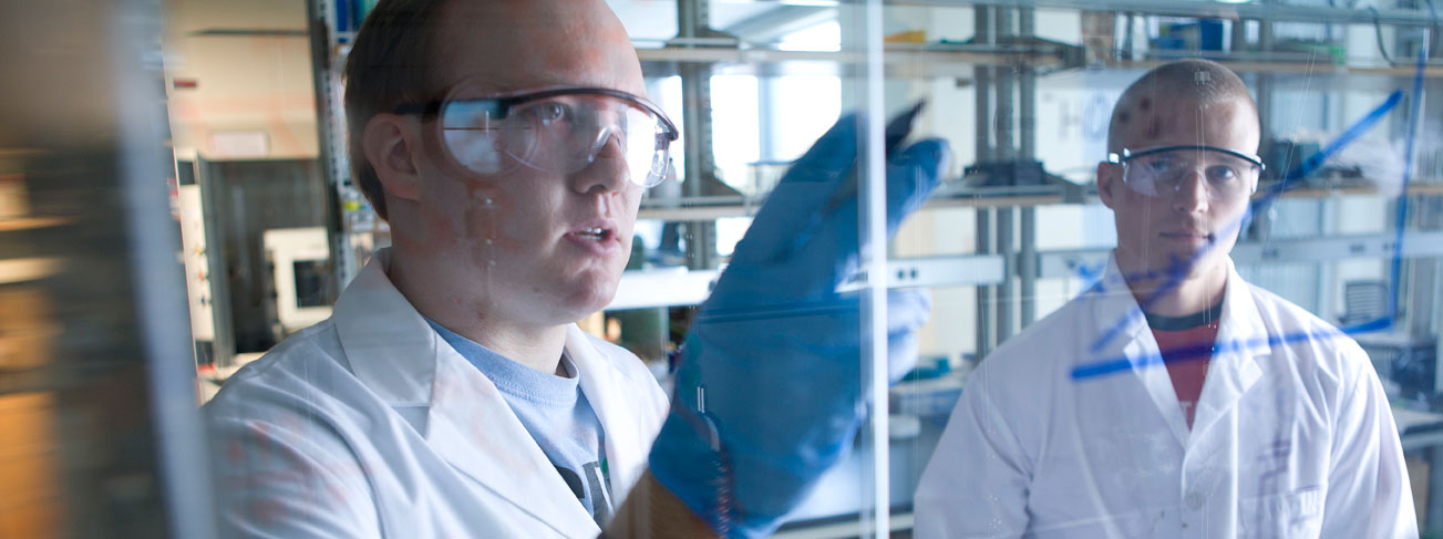 two students review formulas written on clear hood